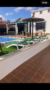 a pool with lounge chairs and an umbrella on a patio at Villa 20 in Caleta De Fuste