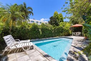una piscina con 2 sillas de césped y una mesa en Beautiful Apt in Victoria Park (Las Olas Blvd), en Fort Lauderdale