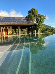 a swimming pool with a house with solar panels on it at Green Fiji Plantation Villa in Taveuni 