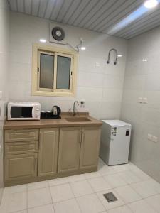 eine Küche mit einer Spüle und einer Mikrowelle in der Unterkunft بيست تريب فالنسيا in Dschāzān