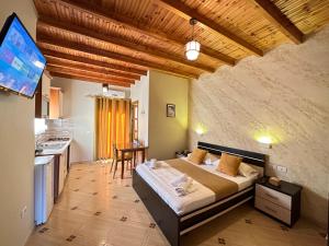 a bedroom with a bed and a kitchen with a television at Vila Arial in Vlorë