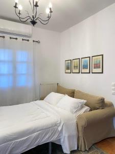 a bedroom with a bed with white sheets and a chandelier at Nereid Skyros House in Skiros