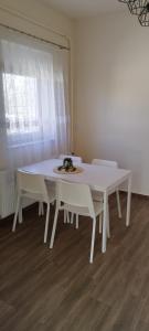 uma mesa branca e cadeiras num quarto com uma janela em Stadion Apartman em Eger