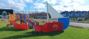 a playground with colorful play equipment on the grass at Pokoje Gościnne in Łeba