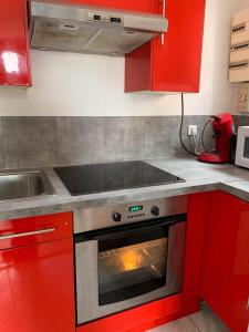 uma cozinha com armários vermelhos e um forno em Studio avec vue sur le lac jardin clos et wifi a Conflans Sainte Honorine em Conflans-Sainte-Honorine