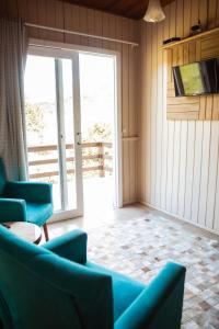 sala de estar con sillas azules y puerta corredera de cristal en Recanto das Águas - Urubici - SC, en Urubici