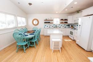 a kitchen with a table and chairs and a refrigerator at NH301, Driftwood Dreaming- Hot Tub, Oceanside, Close to Ocean! in Nags Head