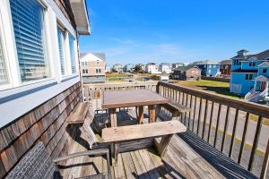 eine Holzterrasse mit einem Picknicktisch auf dem Balkon in der Unterkunft NH301, Driftwood Dreaming- Hot Tub, Oceanside, Close to Ocean! in Nags Head