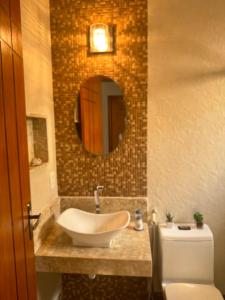 W łazience znajduje się umywalka, toaleta i lustro. w obiekcie Serra Mar Suítes,Lofts, e casas à 300 metros das praias w mieście Arraial do Cabo