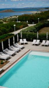 a pool with chaise lounge chairs and a bunch ofvisorvisor at Hôtel La Plage 5 étoiles La Grande Motte in La Grande Motte