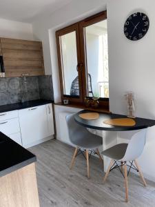 a kitchen with a table and chairs and a clock on the wall at Apartament CARPANO, Ogrodnicza 7 / KARPACZ in Karpacz