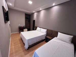 a hotel room with two beds and a flat screen tv at Regis Hotel II in Registro