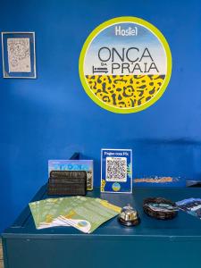 una mesa azul con un cartel en una pared azul en Onça da Praia Hostel, en Vitória