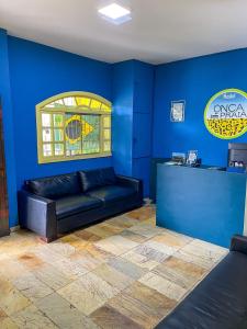 a blue room with a black leather couch and a counter at Onça da Praia Hostel in Vitória