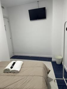 1 dormitorio con 1 cama y TV en la pared en Rooms Mediavilla, en Madrid