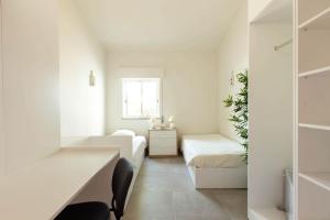 a white room with two beds and a desk at A Casa da Porta Azul in Porches