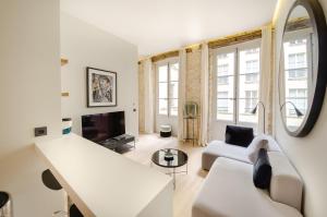 Il comprend un salon blanc doté d'un canapé et d'une télévision. dans l'établissement TUILERIES - VENDOME, à Paris