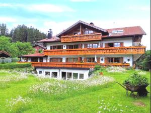 una gran casa en una colina con un campo de flores en Ferienresidenz "Alpin Chic", en Bolsterlang