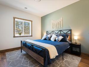 - une chambre avec un lit doté de draps bleus et une fenêtre dans l'établissement Courtside Cabin, à Nisswa