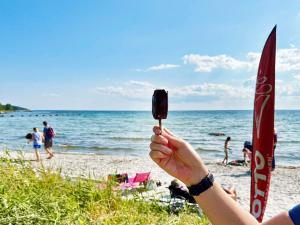 a person holding up a piece of ice cream at the beach at Holiday home SÖLVESBORG V in Sölvesborg