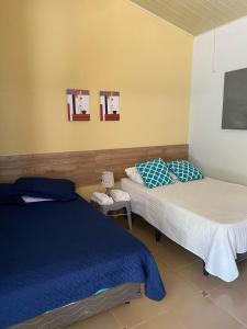 a bedroom with two beds and two pictures on the wall at Casa Pueblo Ocú in El Hatillo
