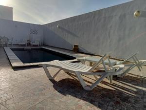 a pool with a lounge chair next to a swimming pool at Villa phare 1 Midoun in Midoun