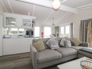 a living room with a couch and a kitchen at Caban Tywod in Pwllheli