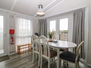 a dining room with a white table and chairs at Caban Tywod in Pwllheli