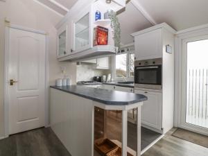 a kitchen with white cabinets and a blue counter top at Caban Tywod in Pwllheli