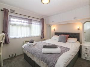 a bedroom with a large bed with towels on it at Caban Tywod in Pwllheli