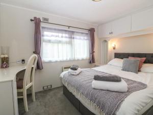 a bedroom with a bed and a desk and a window at Caban Tywod in Pwllheli