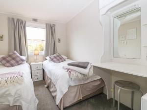 a bedroom with two beds and a desk and a mirror at Caban Tywod in Pwllheli