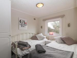 a bedroom with two beds and a window at Caban Tywod in Pwllheli