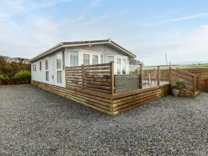 a manufactured home with a deck and a house at Caban Tywod in Pwllheli