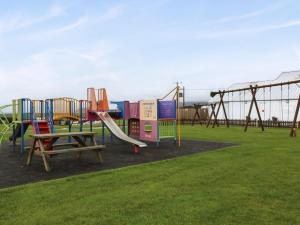 a playground with a slide in a park at Caban Tywod in Pwllheli