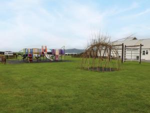 a playground in a park with a grass field at Caban Tywod in Pwllheli