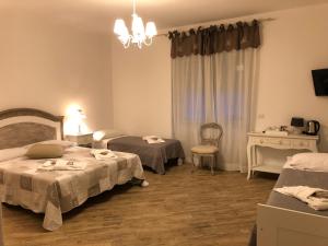 1 dormitorio con 2 camas, mesa y lámpara de araña en City Garden Guest House en Olbia