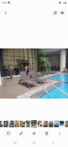 a person sitting on a bench next to a swimming pool at Grand Canal Penthouse! in Manila