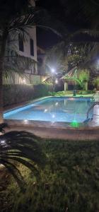 una piscina notturna con luci in cortile di Villa L'Oasis a Ouagadougou