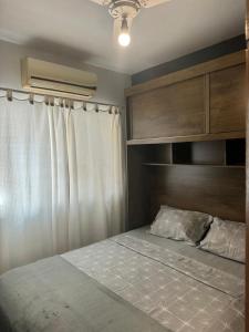 um quarto com uma cama e uma cabeceira em madeira em Serra Mar Suítes,Lofts, e casas à 300 metros das praias em Arraial do Cabo