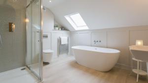 a bathroom with a tub and a sink and a skylight at Penrhyn Isa Un in Aberffraw