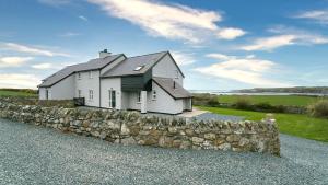 a white house on top of a stone wall at Penrhyn Isa Un in Aberffraw