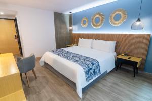 GHL Hotel Abadia Plaza في بيريرا: غرفة فندقية بسرير كبير وكرسي