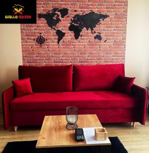 een rode bank voor een stenen muur met een tafel bij Giallo-Rosso in Białystok
