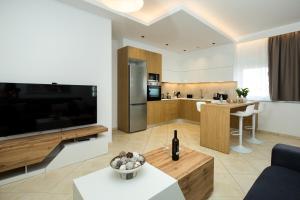 a living room with a large television and a kitchen at Kiss-ammos Apartments in Kissamos