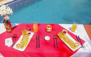 Nindirí的住宿－Hotel Amigo Nicaragua，一张桌子,上面有食物和饮料,放在红色桌布上