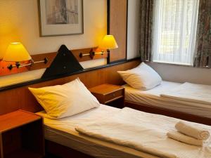 two beds in a small room with two lamps at Hotel zur Eiche in Meerane