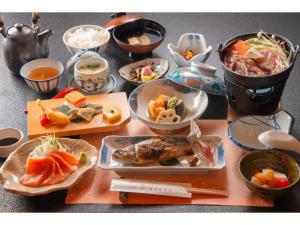 Nakanoyu Onsen Ryokan - Vacation STAY 07500v في ماتسوموتو: طاولة مع أطباق من الطعام وأوعية من الطعام