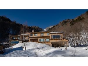 une maison dans la neige devant une montagne dans l'établissement Nakanoyu Onsen Ryokan - Vacation STAY 07485v, à Matsumoto