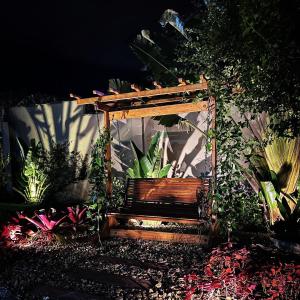 a wooden bench in a garden with plants at Regis Hotel II in Registro